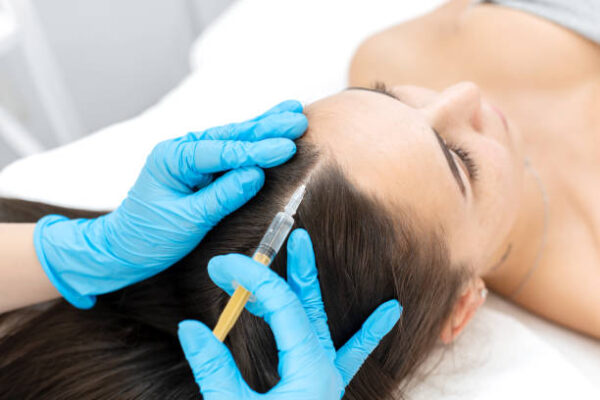 Close-up, the beautician makes injections of vitamins into the scalp for strengthening the hair